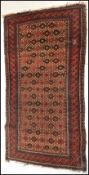 A 20th Century woolen hand knotted carpet floor rug on red ground, central geometric panel