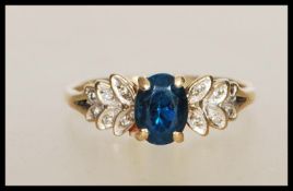 An English hallmarked 9ct gold dress ring set with an oval cut blue stone with graduating foliate