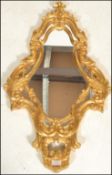 A 20th Century gilt rococo style wall mirror having a symmetrical reeded gilt frame with scrolled