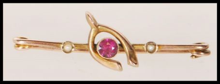 A 19th Century Victorian brooch stamped 9ct gold moulded as a wishbone set with a central faceted