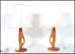 A pair of mid 20th century retro teak table lamps of angular sculptured form raised on circular