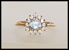 An English hallmarked 9ct gold ring set with a heart cut blue stone with a halo of white accent
