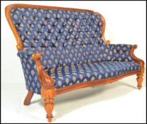A 20th Century contemporary Victorian style walnut spoon back sofa being raised on carved cabriole