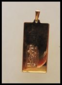 A hallmarked 9ct yellow gold rectangular pendant depicting a small figure carrying a child with J