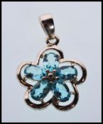 A hallmarked 9ct white gold pendant in the form of a flower set with five oval faceted cut blue