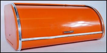A retro 20th Century cylinder roll top wall mountable bread bin, original orange finish, printed