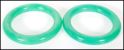 A pair of 20th Century Chinese jade type slave bangles of typical form. Interior diameter 6cm.