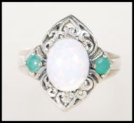 A stamped 925 silver ladies dress ring set with an opal flanked by two green stones on a