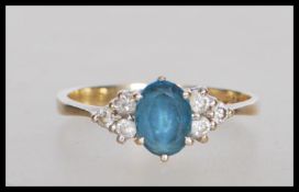 An English hallmarked 9ct gold ring set with an oval cut blue stone flanked with six round cut white