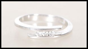 A stamped 750 18ct white gold ring of wrap around design set with three round cut diamonds. Diamonds