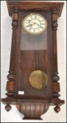 A 19th Century Vienna wall clock set within a mahogany case with glazed panel door flanked by turned