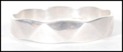 An English hallmarked bangle bracelet decorated with triangular facets. Hallmarked london 1992.