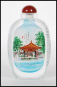 A Chinese glass scent bottle having interior painted decoration depicting a river scene with outdoor
