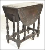 A early 20th Century carved oak drop leaf dining table being raised on turned legs united by