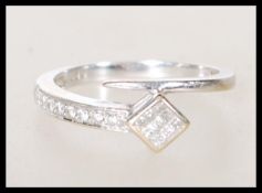 A stamped 750 18ct white gold tapering wrap around ring set with round and square cut diamond accent
