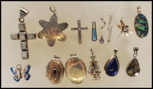 A collection of silver pendants to include a a locket of oval form set with an oval cut red stone, a