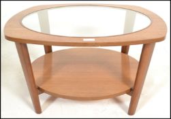 A vintage 20th century teak wood G-Plan style Astral coffee table of oval form with inset glass