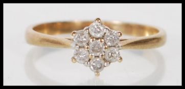 A stamped 9ct gold ring having a flower head cluster of round cut diamonds. Diamonds estimated at