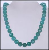 A 20th Century Chinese beaded and knotted green jade necklace, with silver white metal lobster