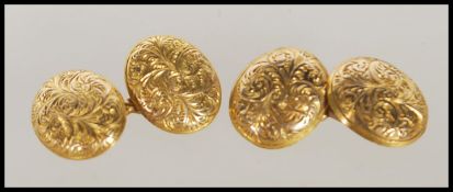 A pair 9ct yellow gold cuff links of oval form having engraved foliate and swirl decoration.