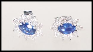 A pair of 18ct white gold earrings set with central oval faceted cut sapphire with a halo of