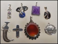 A selection of silver pendants to include an elephant pendant set with a lapis lazuli bead, a