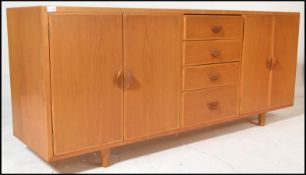 A mid century Ercol manner oak sideboard credenza being raised on stub turned legs with a wide and