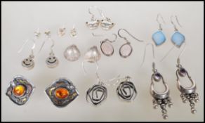 A collection of silver earrings including stud and drop earrings to include a pair of amber cabochon
