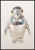 A stamped sterling silver pincushion in the form of a penguin set with glass eyes having a red