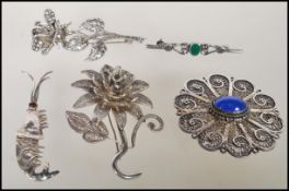 A collection of silver brooches to include a bar brooch set with a malachite panel, a rose brooch