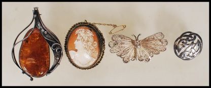 A group of four brooches to include cameo brooch depicting a neoclassical lady with a chailike