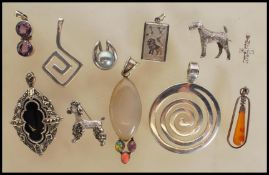 A selection of silver pendants to include two spiral design pendants, a marcasite and onyx panel