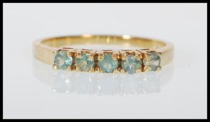 A hallmarked 9ct gold ring set with five round cut green stones. English hallmarks for Birmingham