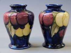 Moorcroft pair of baluster pedestal cases in Wisteria pattern on a navy blue ground, 9.5cm tall