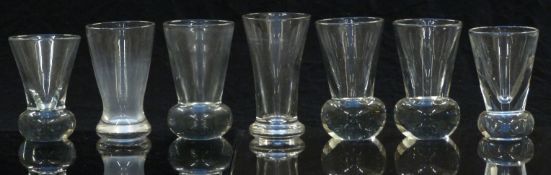 Seven various 19thC and later clear firing glasses, some raised on bulbous bases, largest 11cm tall.