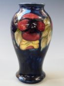 William Moorcroft pedestal baluster vase in Pansy pattern on a navy blue ground, signed and