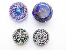 Four Perthshire glass paperweights comprising one faceted example with red flowers on a blue ground,