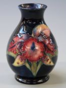 Moorcroft pedestal vase decorated with orchids on a navy blue ground, 10cm tall