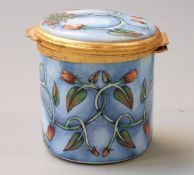 Moorcroft enamel cache pot with hinged lid, decorated with intertwined flowers on pale blue