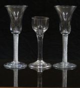 A pair of clear drinking glasses with air twist stems and waisted bowls, raised on conical feet,