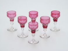 A set of six flash overlaid cranberry glass drinking glasses with cut decoration raised on knopped