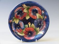 Moorcroft small charger in Pansy pattern on a navy blue ground, diameter 22cm
