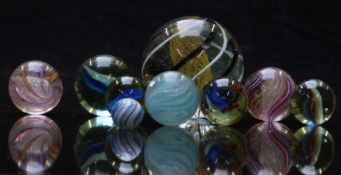 Nine glass marbles including one blue onionskin, two with multi-coloured spirals surrounding