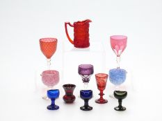 Eleven pieces of coloured glass including flash overlaid cut cranberry glass drinking glasses,