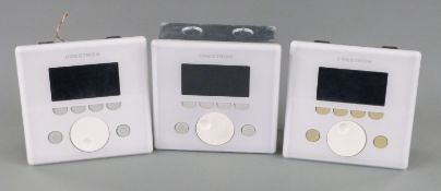 Three white Creston APAD wall mounted LCD controllers for Creston's Adagio home entertainment