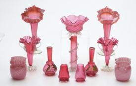 Twelve cranberry glass vases including two pairs with crimped rims, two with gilded decoration and a