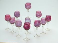 Eleven cranberry glass wine glasses with engraved decoration of fruit and foliage raised on clear