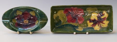 Moorcroft pen tray and ashtray in Hibiscus and Clematis patterns on a green ground, 20 x 9cm