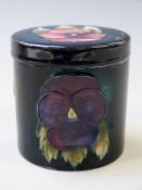 Moorcroft lidded cylindrical jar in Pansy pattern on a navy blue ground, 9cm tall