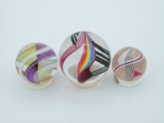 Three Teign Valley Glass (TVG) glass marbles all with multi-coloured glass spirals, largest 34.3mm